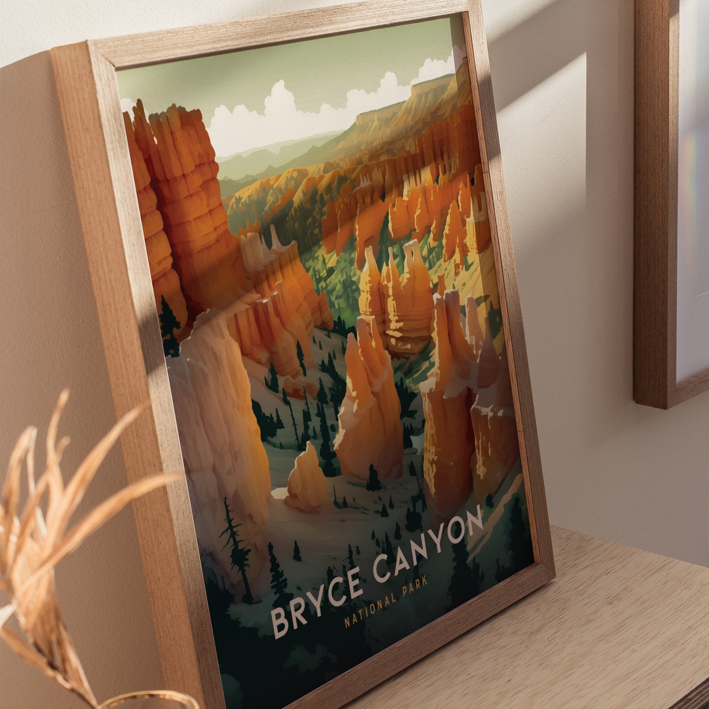 Framed print featuring a vibrant illustration of Bryce Canyons iconic hoodoos in warm orange and green tones, displayed on a wooden surface. Shadows fall across the wall and artwork.