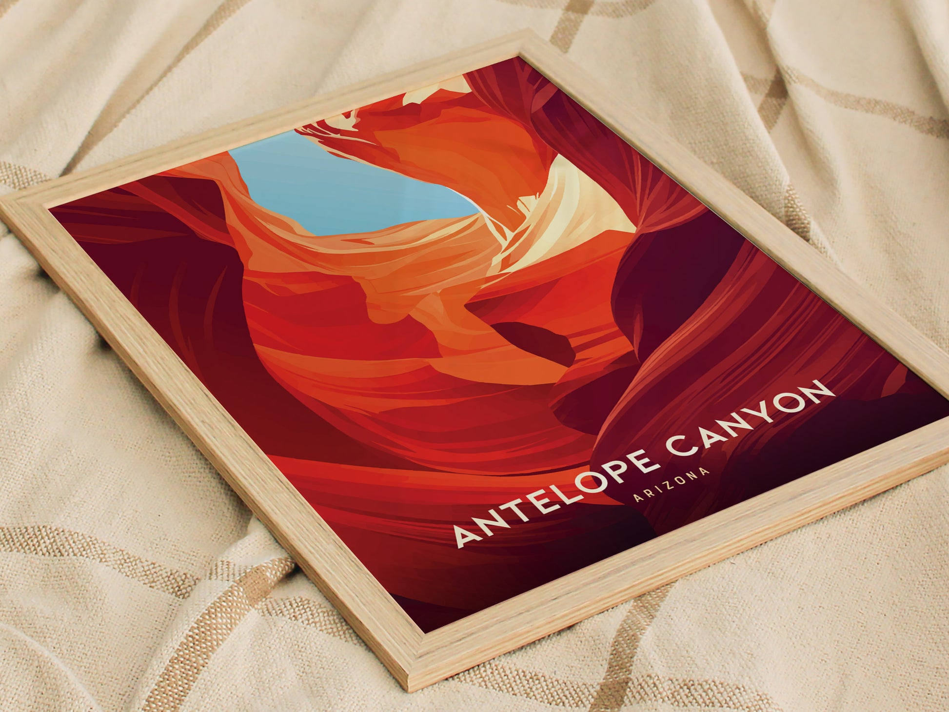A framed poster of Antelope Canyon with vibrant red and orange sandstone formations against a blue sky, placed on a textured beige fabric.