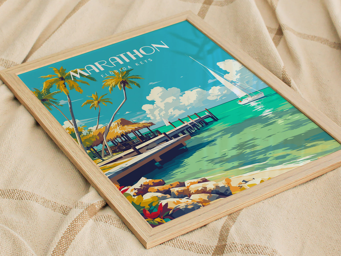 A framed poster of Marathon Florida Keys featuring palm trees, a pier, and turquoise waters, placed on a textured fabric surface. The artwork conveys a serene coastal scene.
