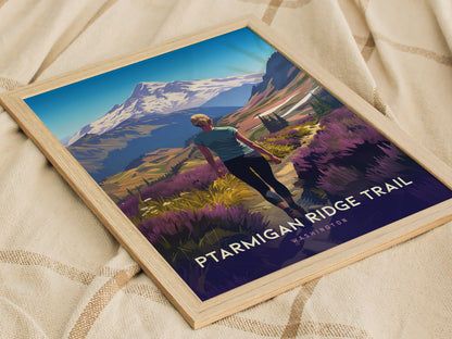 A framed poster depicting a hiker on the Ptarmigan Ridge Trail, surrounded by vibrant wildflowers with Mt. Bakers snow-capped peak in the background, rests on a beige fabric.