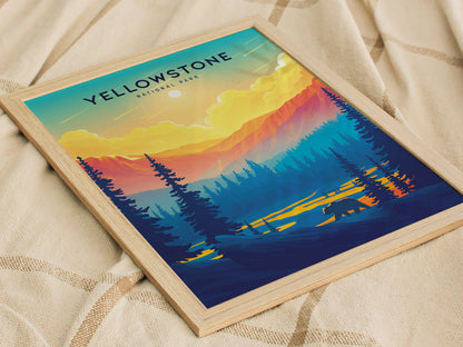 A framed poster depicting a vibrant sunset over Yellowstone National Park, featuring colorful mountains, silhouetted trees, and a bear. The artwork rests on a textured beige fabric.
