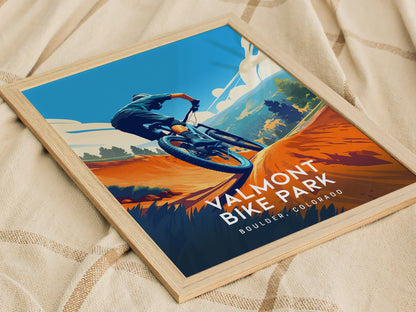 Framed poster of a mountain biker on an orange trail, set against a backdrop of trees and blue sky, with Valmont Bike Park Boulder Colorado text.