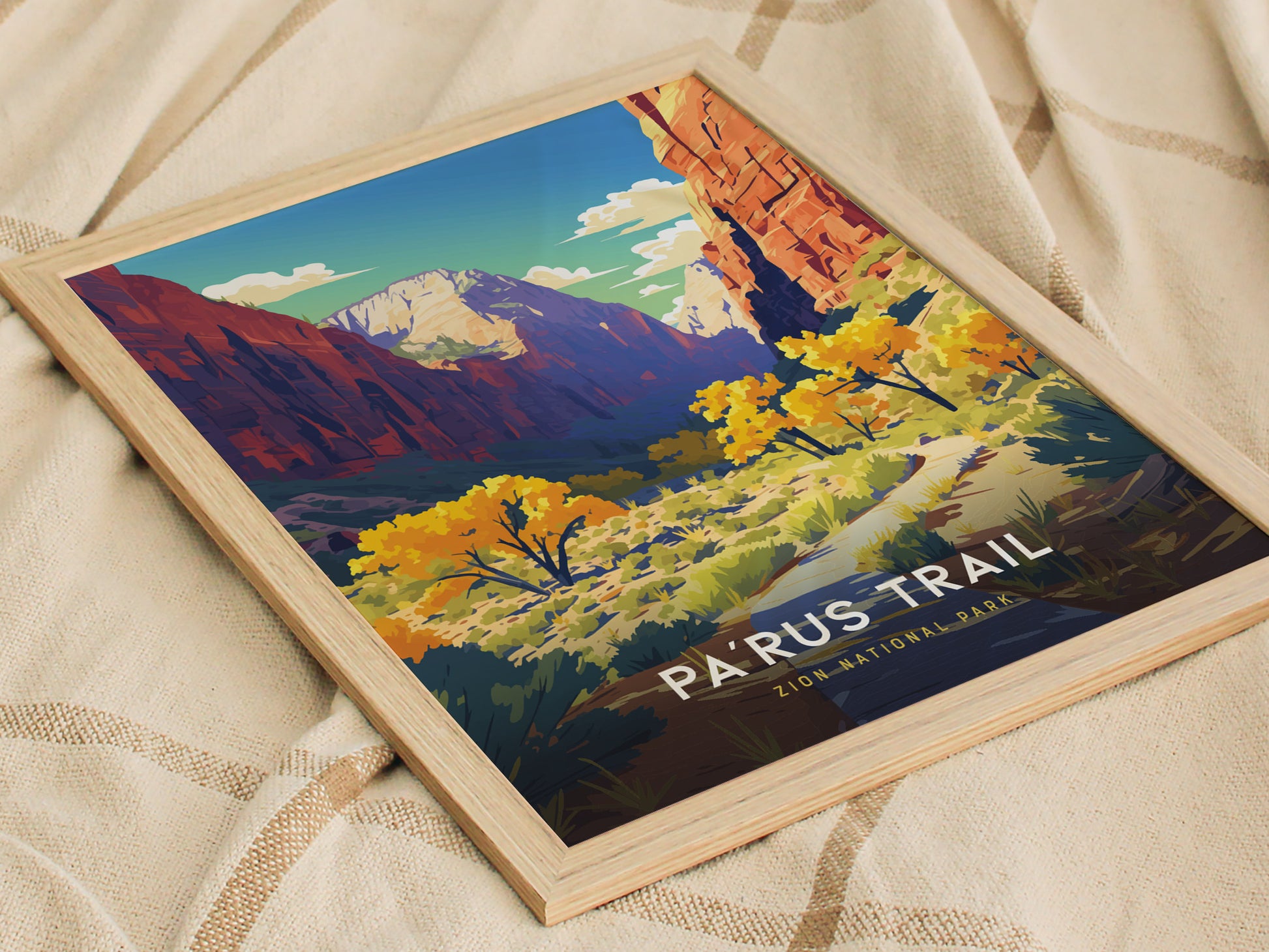 Framed poster of Parus Trail, Zion National Park, featuring vibrant autumn foliage and towering red cliffs under a bright blue sky, placed on a textured beige fabric.