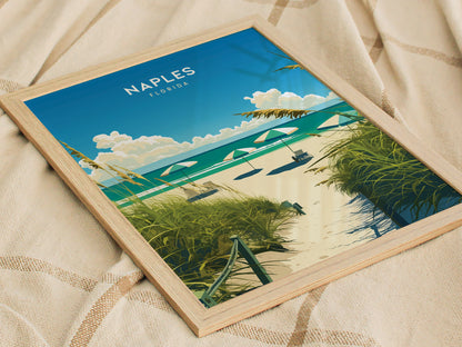 Framed artwork depicting a beach scene with sandy path, green foliage, umbrellas, and a clear blue sky, placed on a textured fabric background. Text reads Naples Florida.
