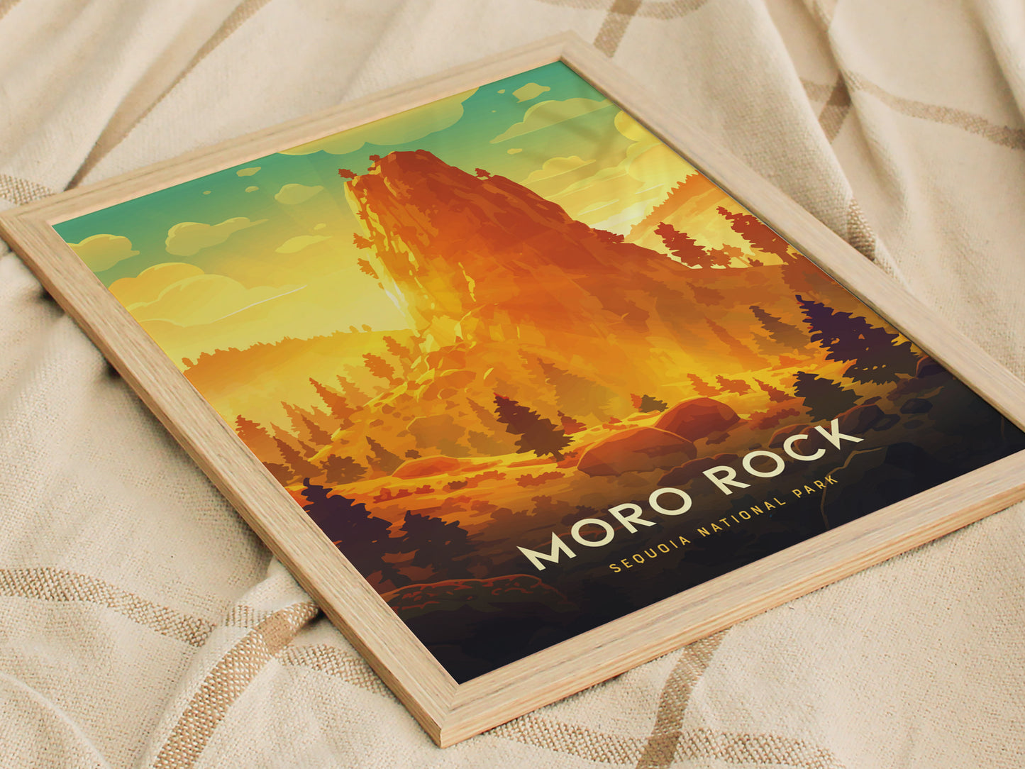 Framed poster featuring a vibrant illustration of Moro Rock in Sequoia National Park, with warm sunset hues and silhouetted trees, resting on a beige textured fabric.