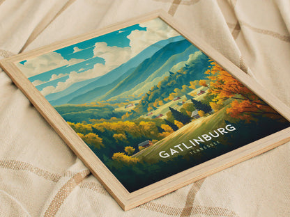 A framed poster of Gatlinburg, Tennessee, showcasing a vibrant landscape with lush forests, rolling hills, and clear skies, placed on a textured beige fabric surface.