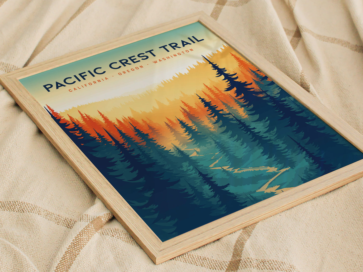 A framed Pacific Crest Trail poster depicts a stylized landscape with vibrant orange and blue trees, set against a gradient sky. The text includes California, Oregon, Washington.