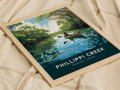 A framed poster of Phillippi Creek shows a kayaker paddling through a serene, mangrove-lined waterway under a blue sky. The text reads Phillippi Creek, Sarasota, Florida.