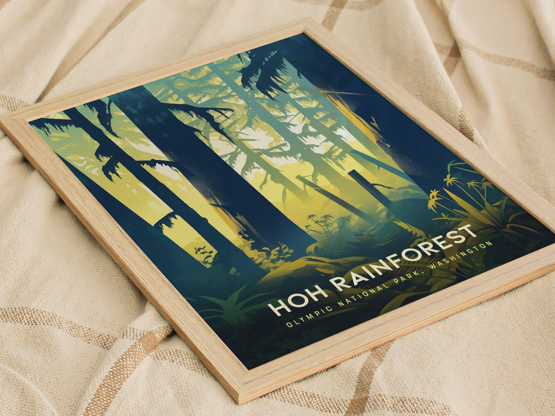 Framed artwork depicting stylized trees and foliage in a forest, with Hoh Rainforest Olympic National Park Washington text. The poster is set on a textured fabric surface.