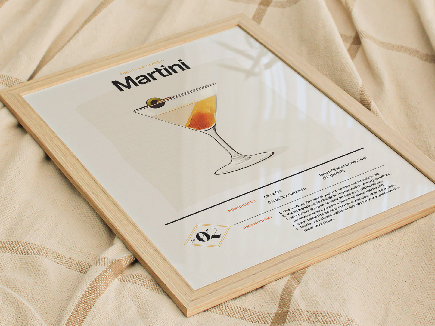 Framed martini cocktail poster with a classic dry martini illustration and recipe text, resting on a textured beige fabric. Perfect for home bars and cocktail enthusiasts.