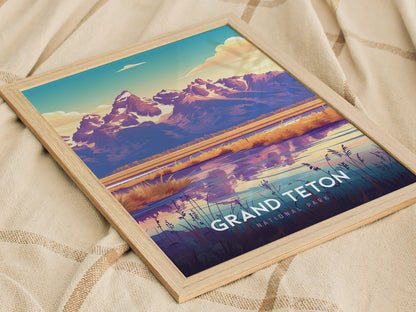 A framed poster of Grand Teton National Park with colorful mountain peaks reflected in a calm lake, laid on a textured fabric. The text reads Grand Teton National Park.