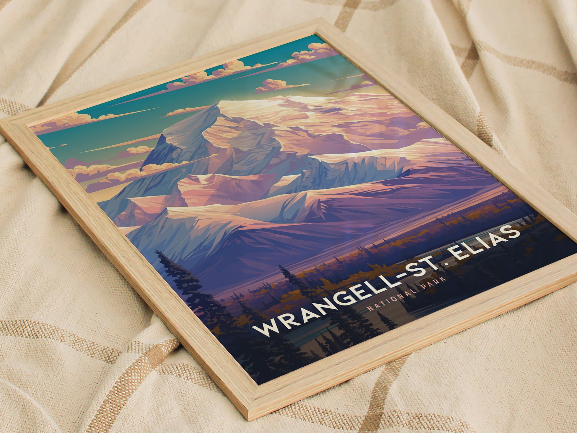 A framed poster depicting a stylized mountain scene with vibrant colors, showcasing Wrangell-St. Elias National Park, rests on a textured beige fabric.