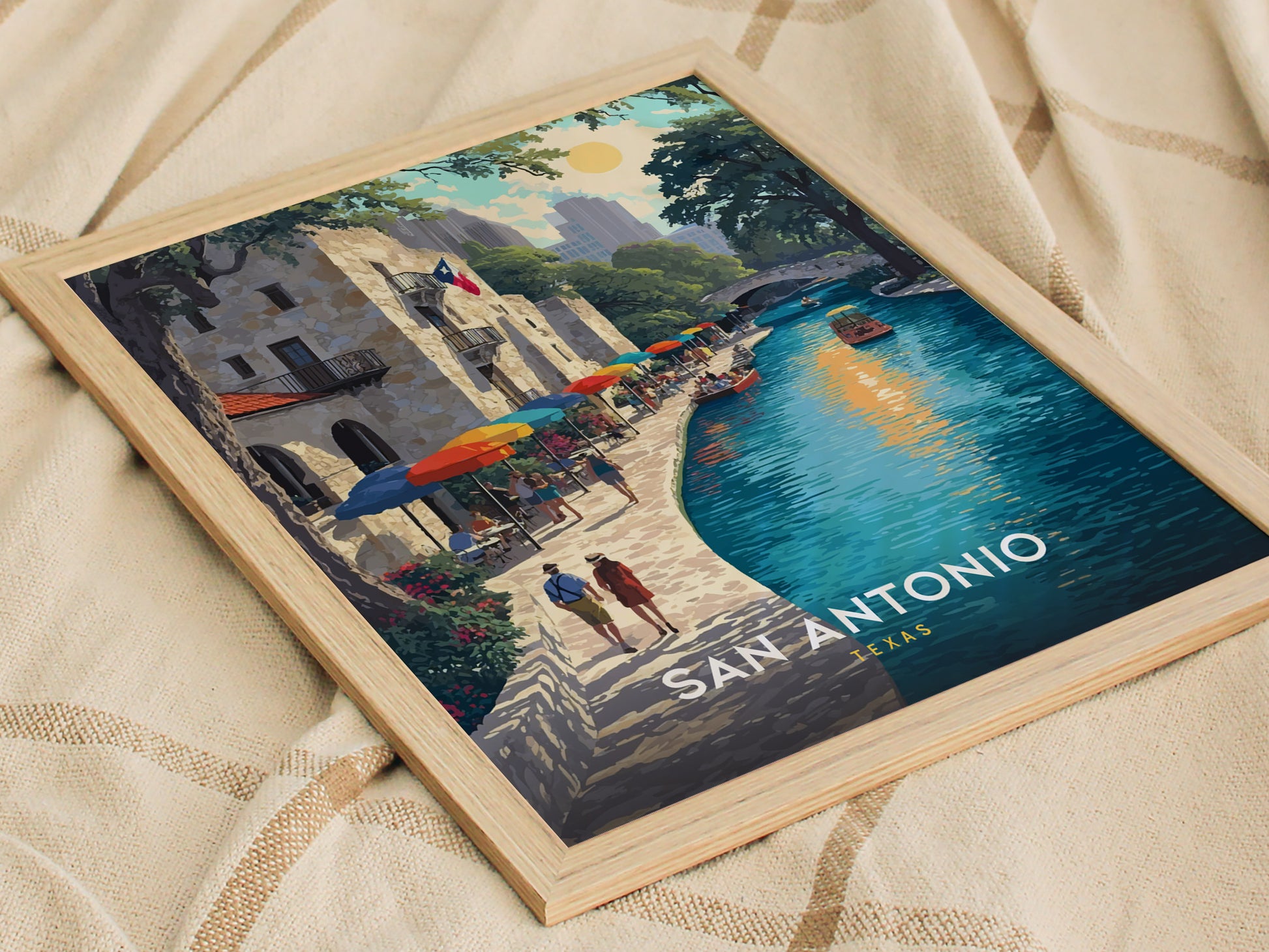 A framed poster depicts a vibrant San Antonio riverwalk scene with colorful umbrellas, people walking, and boats on the water. The words San Antonio Texas are visible.