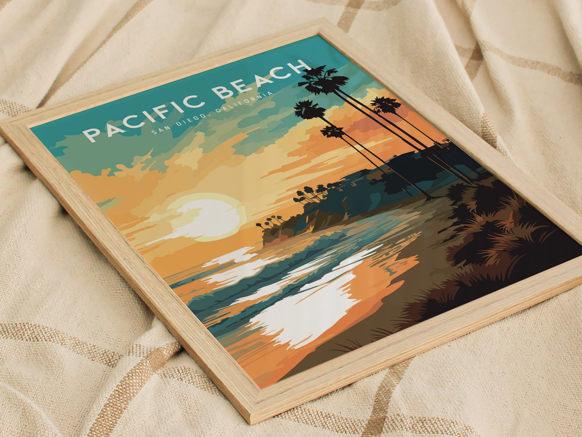 Framed artwork of Pacific Beach, San Diego, featuring a sunset over the ocean with silhouetted palm trees and vibrant colors. The print rests on a textured beige fabric, highlighting a coastal and relaxing vibe.