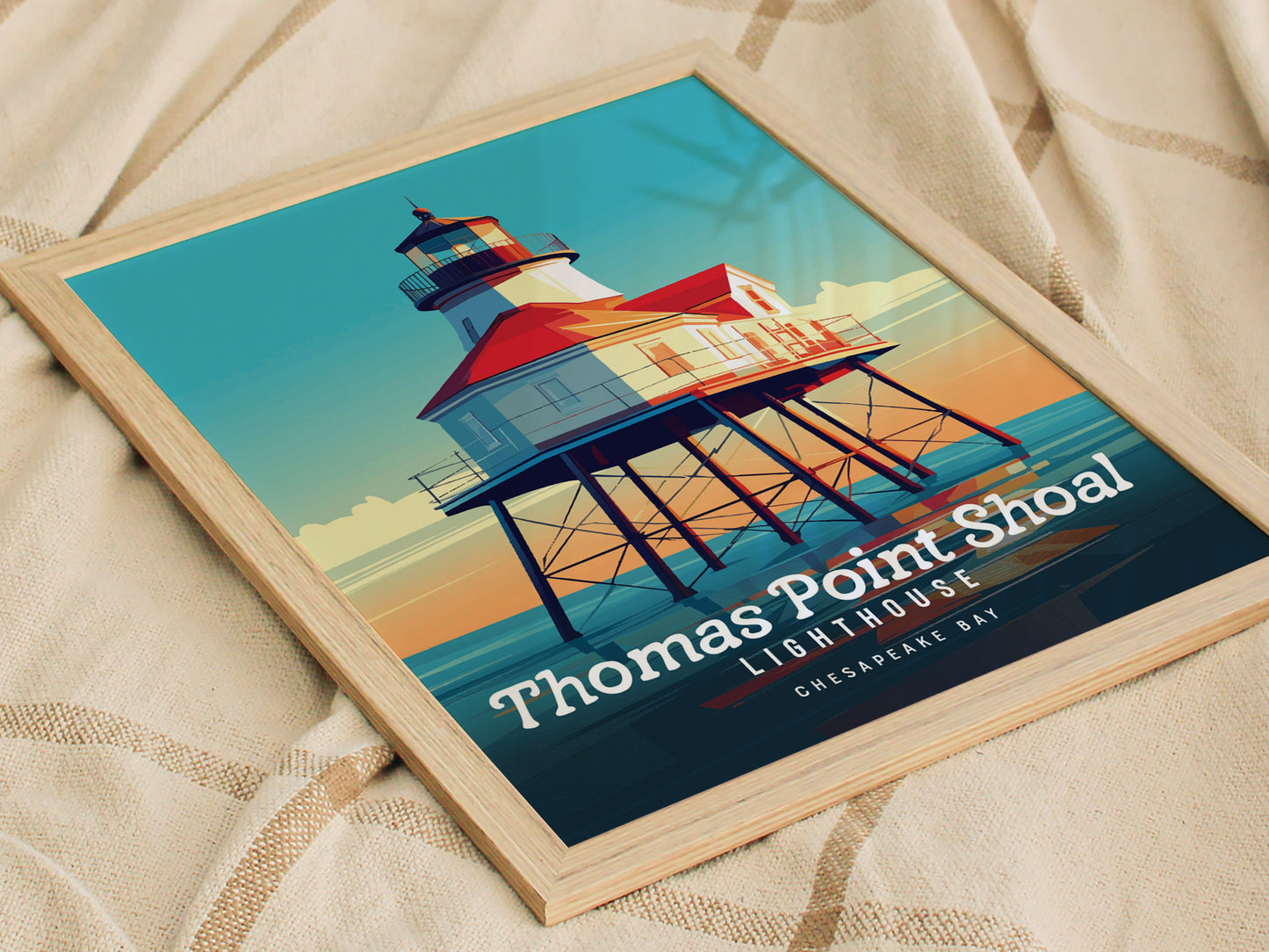 A framed poster of the Thomas Point Shoal Lighthouse, featuring vibrant colors and bold design, rests on a textured beige fabric surface. The text highlights its location in Chesapeake Bay.