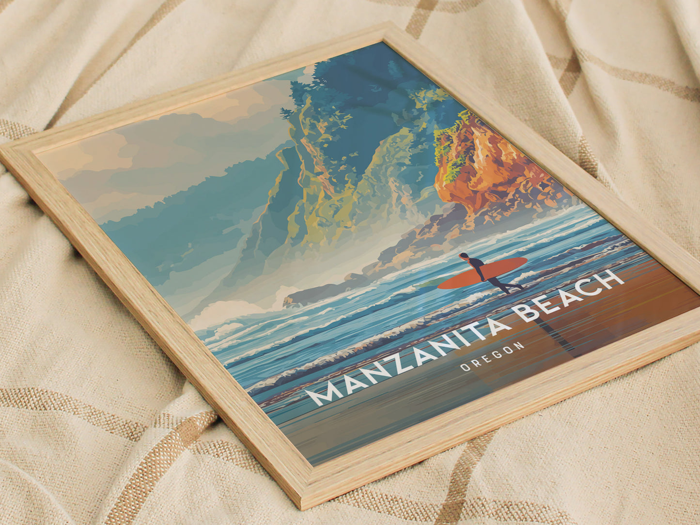 A framed poster of Manzanita Beach in Oregon features a colorful illustration of a surfer with an orange surfboard, positioned against a backdrop of rocky cliffs and vibrant waves.