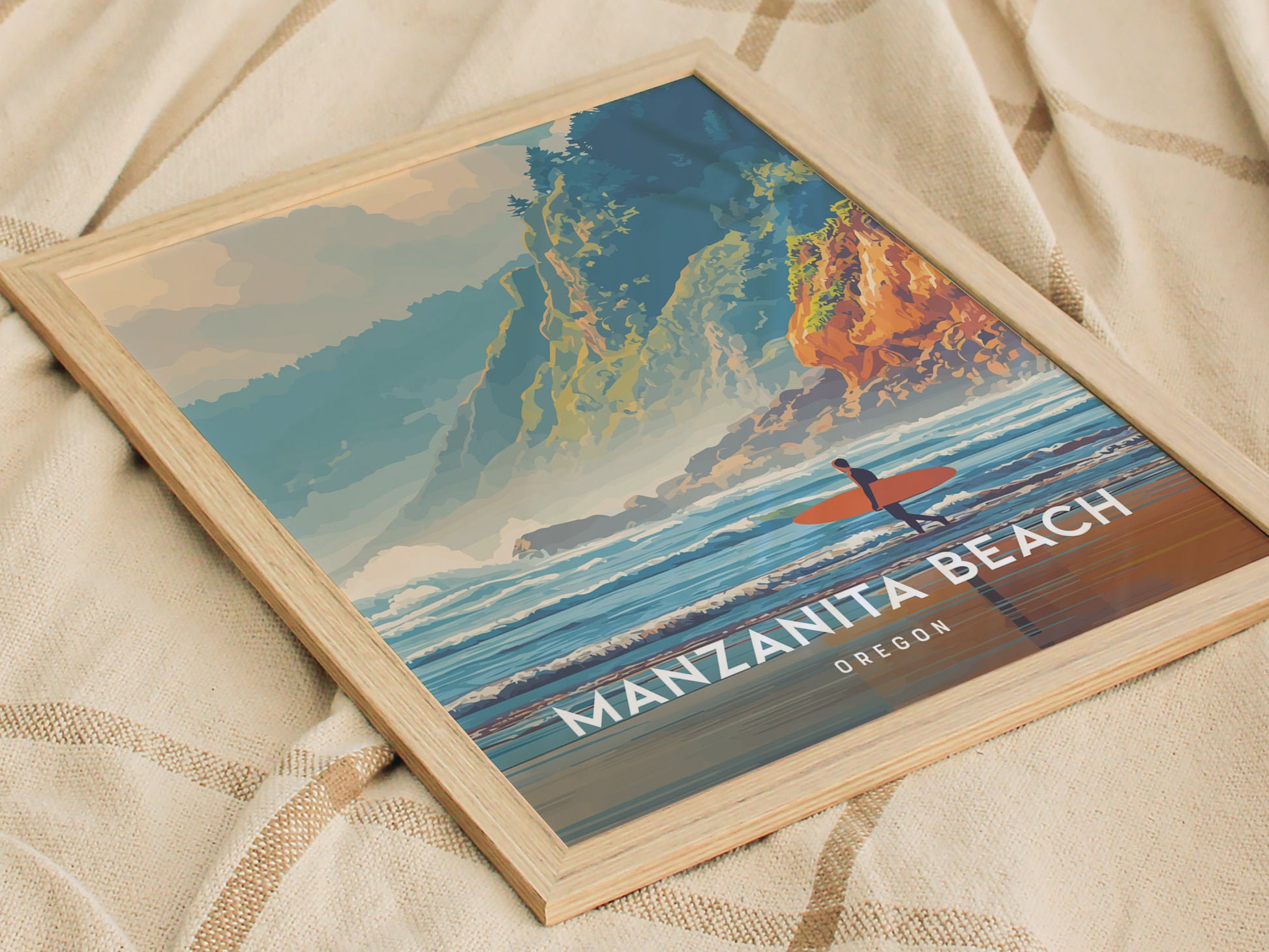 A framed poster of Manzanita Beach in Oregon features a colorful illustration of a surfer with an orange surfboard, positioned against a backdrop of rocky cliffs and vibrant waves.