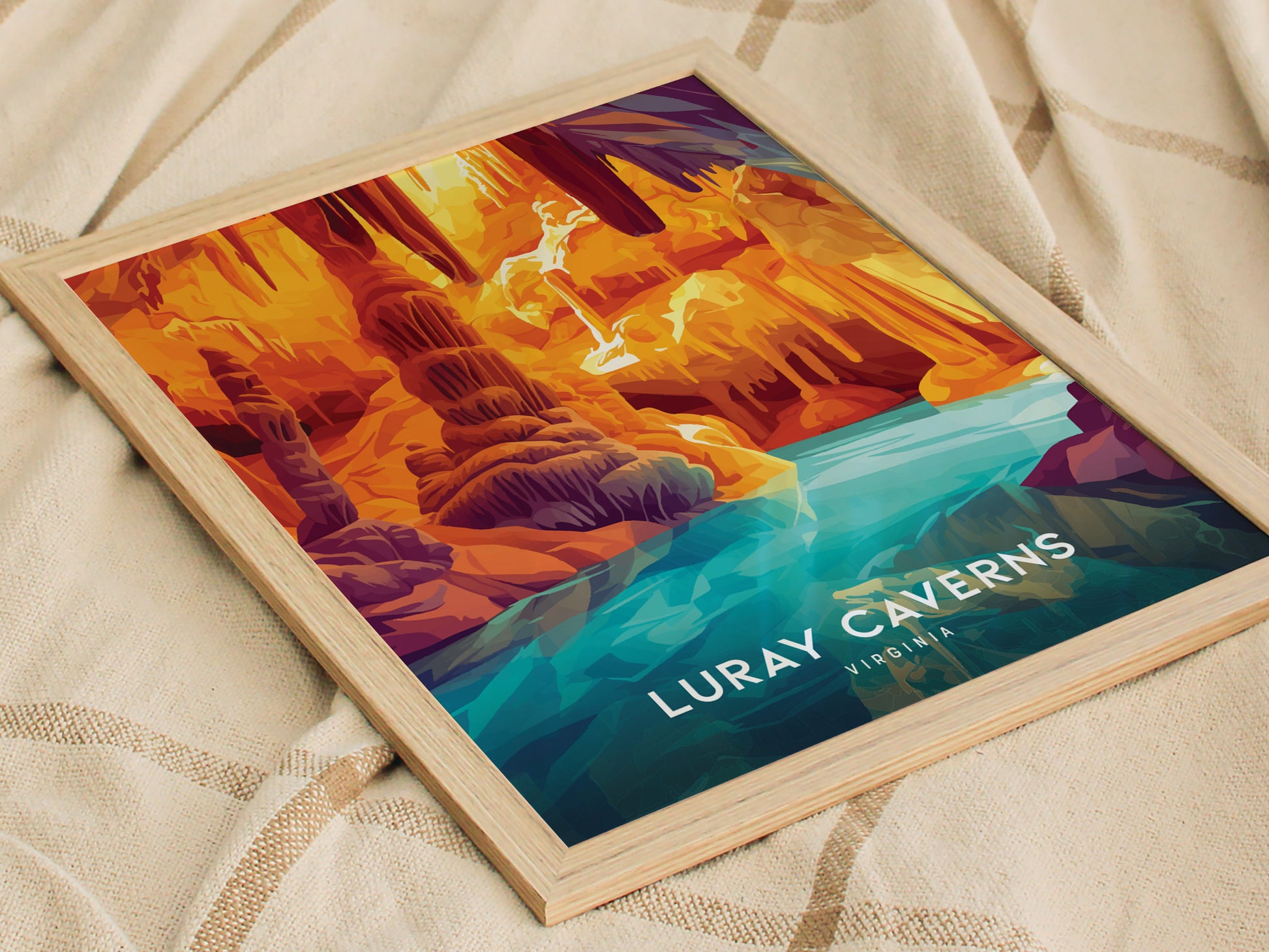 A framed poster featuring a colorful illustration of Luray Caverns with vibrant orange formations and a blue pool, resting on a textured fabric surface.