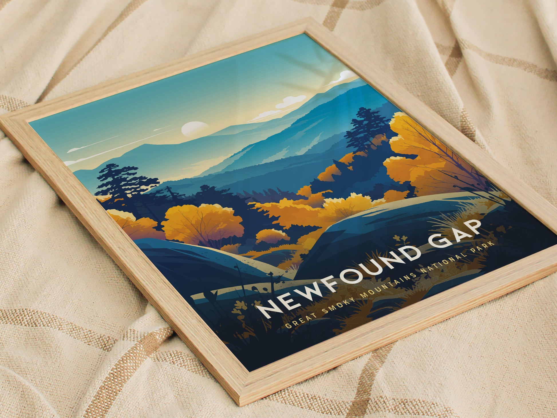 Framed poster featuring a stylized landscape of the Great Smoky Mountains with blue ridgelines, vibrant autumn trees, and a setting sun. The text reads Newfound Gap, Great Smoky Mountains National Park.