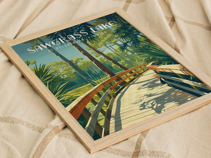 Framed poster of Sawgrass Lake with a wooden boardwalk winding through lush green foliage under a clear sky, placed on a textured beige surface.