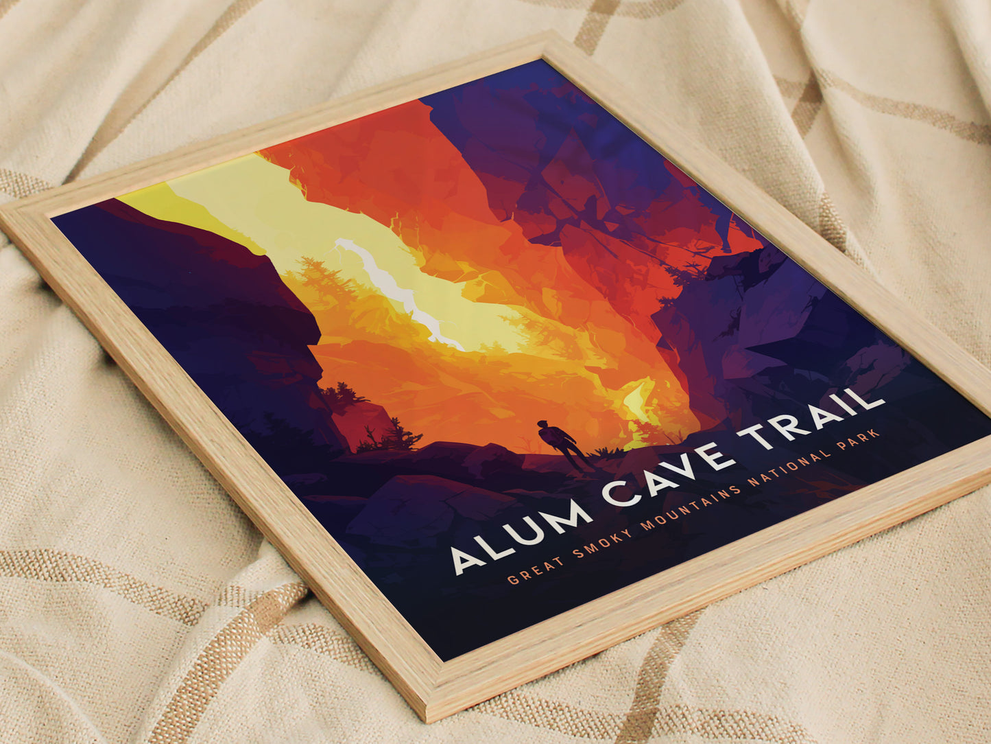 A vibrant poster featuring a hiker silhouette against a dramatic, colorful landscape of the Alum Cave Trail in the Great Smoky Mountains National Park, framed in light wood.