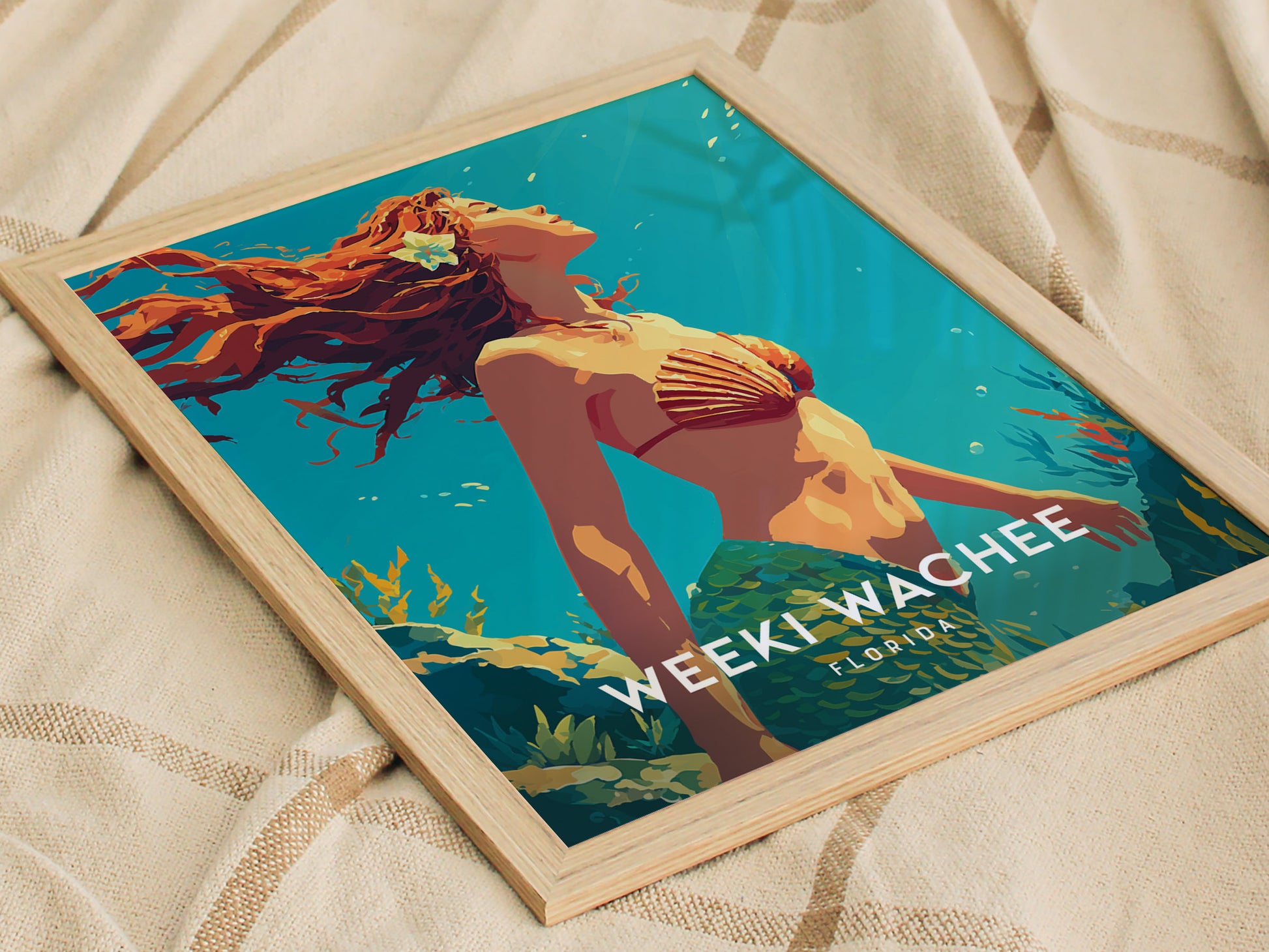A framed poster featuring a vibrant illustration of a mermaid with flowing red hair, wearing a seashell top and a green tail, swimming amidst underwater plants. The text WEEKI WACHEE FLORIDA is prominently displayed at the bottom.