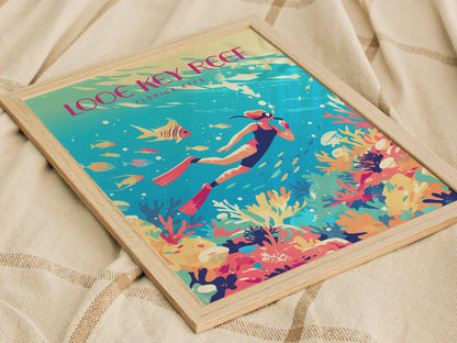 A colorful coral reef poster in a wooden frame shows a snorkeler exploring vibrant sea life, with tropical fish and coral, laid on a textured beige fabric.