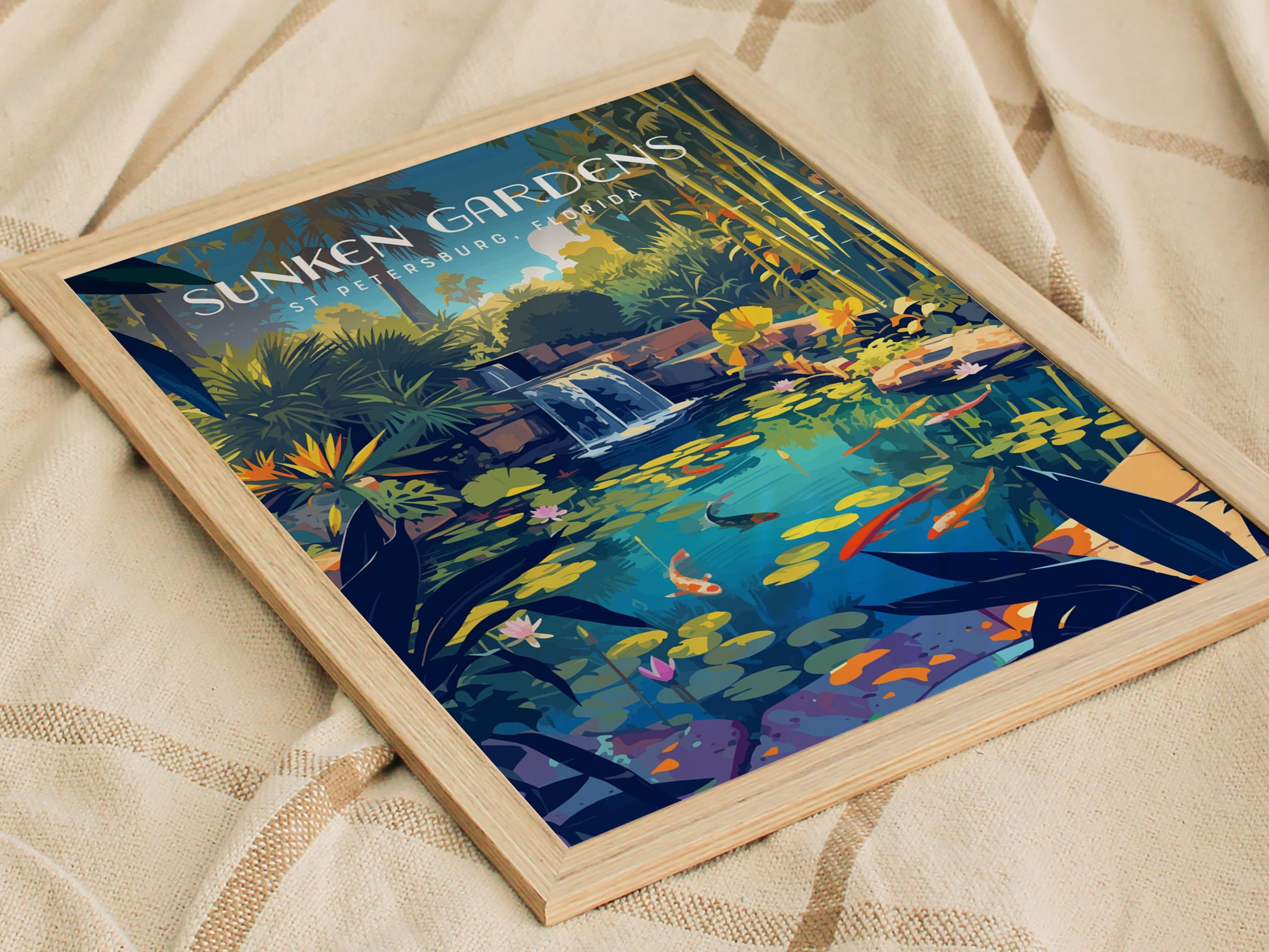A framed poster of Sunken Gardens in St. Petersburg, Florida, featuring a vibrant koi pond with lush tropical foliage, colorful fish, and a small waterfall, set on a fabric surface.