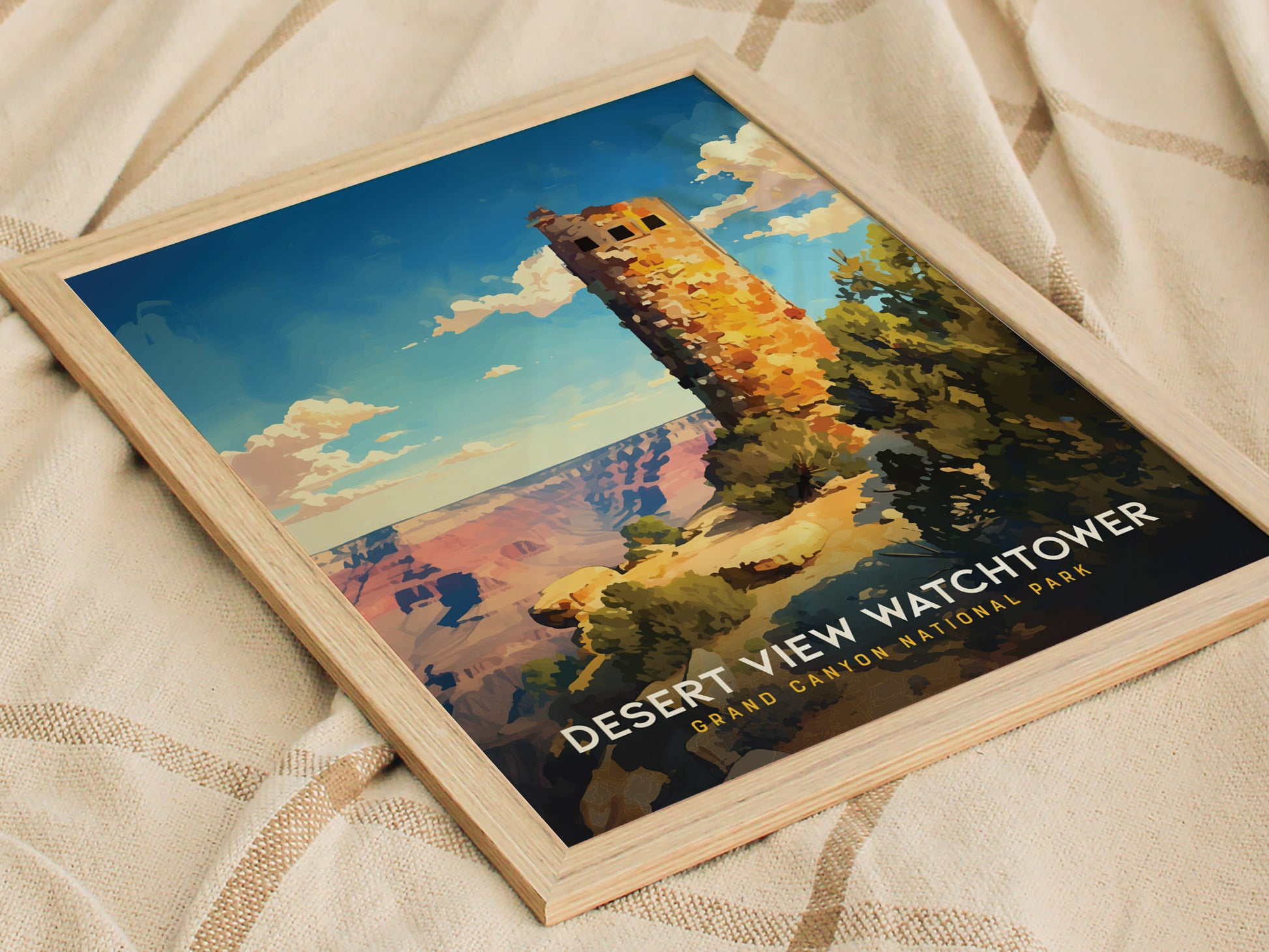 A framed poster of the Desert View Watchtower at Grand Canyon National Park lies on a textured fabric surface, showcasing vibrant colors and a clear blue sky.