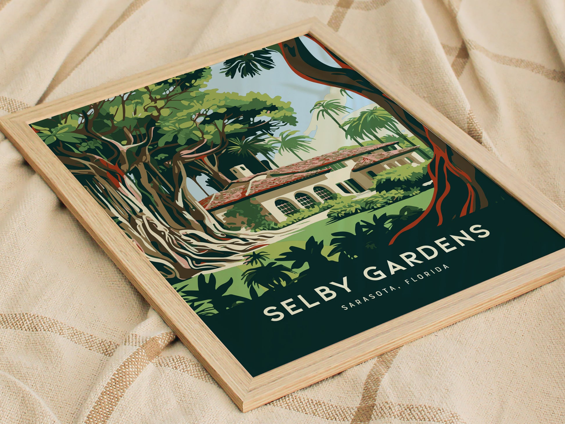 Framed artwork of Selby Gardens in Sarasota, Florida, depicting lush trees and a classic building. The poster is placed on a beige, textured fabric surface.