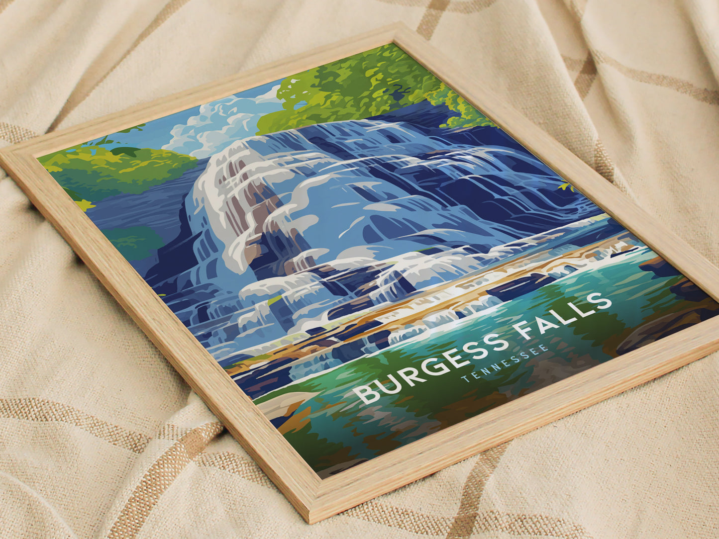 A framed poster of Burgess Falls in Tennessee, featuring cascading waterfalls and lush greenery in a vibrant, modern design, rests on a textured fabric surface.