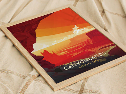 A framed poster depicting a stylized sunset over the red canyons of Canyonlands National Park, with vivid orange and red hues, resting on a textured beige fabric.