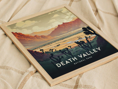 Framed art print depicting Death Valley National Park with vibrant desert landscape, featuring red mountains, cloudy sky, and silhouetted Joshua trees, resting on a textured beige fabric.