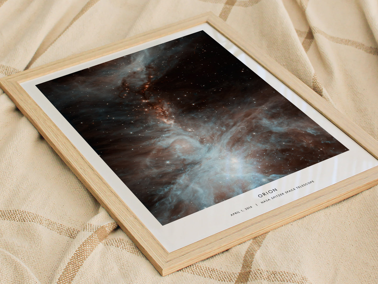 Framed photograph of a nebula on a textured fabric background