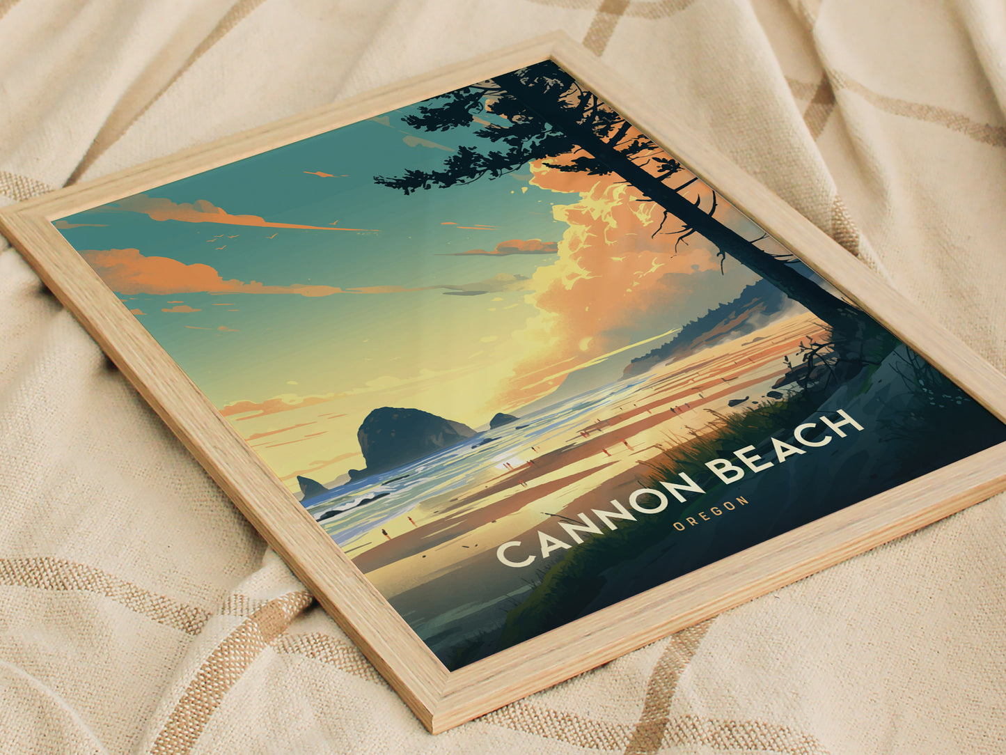 Framed artwork depicting Cannon Beach, Oregon, featuring Haystack Rock at sunset with vibrant skies and ocean waves. The poster is placed on a textured fabric background.