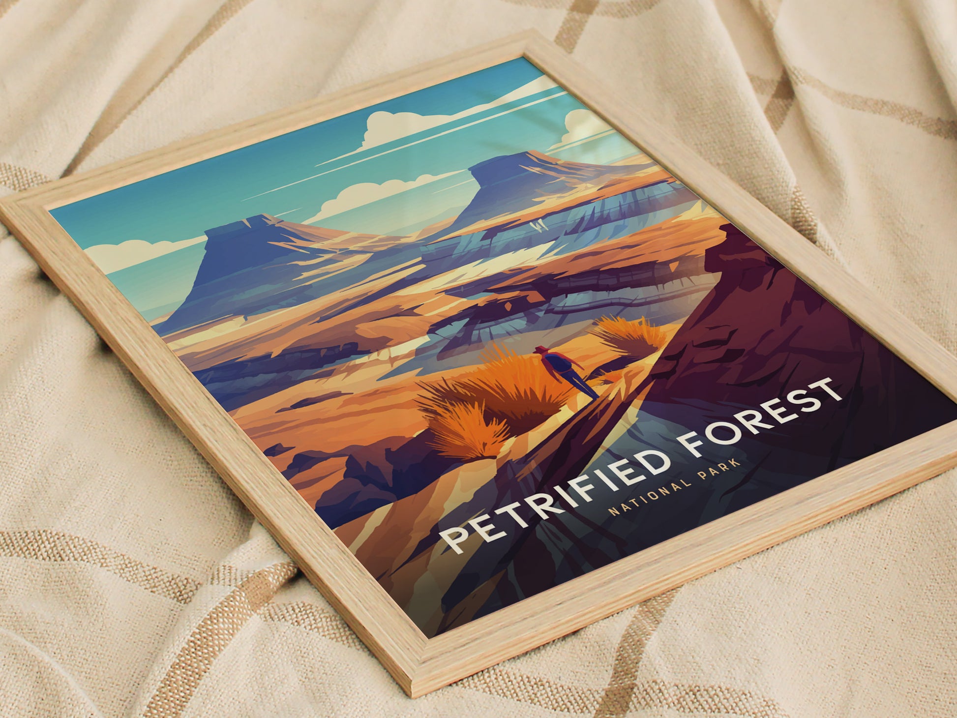 A framed art print of Petrified Forest National Park featuring vibrant desert landscapes with mesas and colorful rock formations, resting on a textured beige fabric.