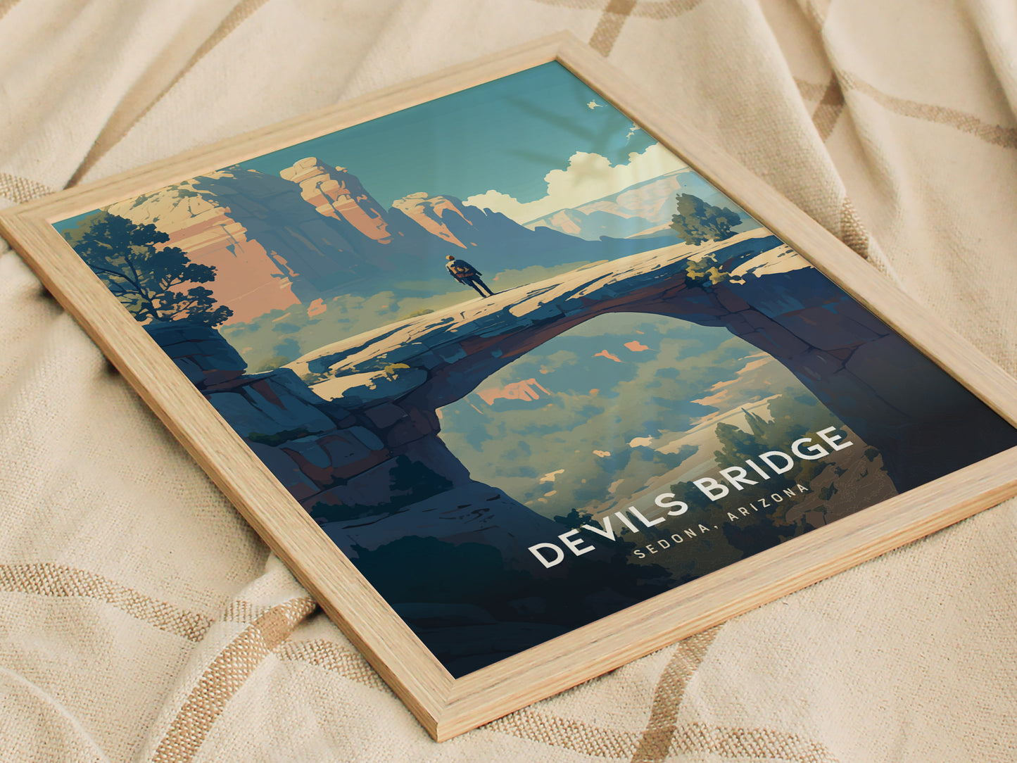 A framed poster of Devils Bridge in Sedona, Arizona, featuring a person standing on the sandstone arch against a backdrop of desert cliffs and a vivid sky.