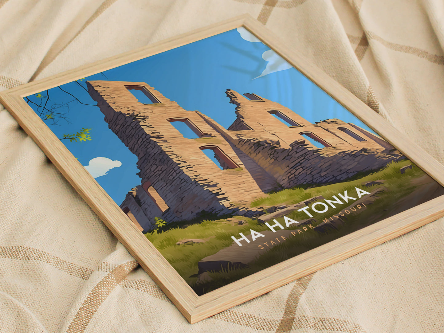 Framed artwork depicting the ruins of Ha Ha Tonka State Park in Missouri, showcasing stone structures against a clear blue sky. The poster rests on a beige, textured fabric.