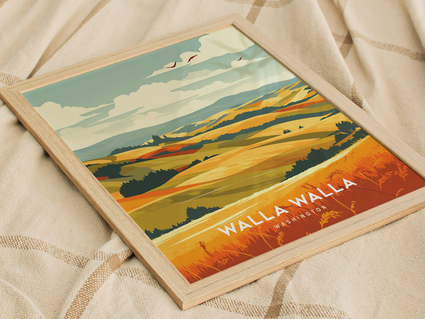 Framed poster depicting stylized rolling hills and vineyards with a vibrant color palette, set on a patterned fabric background. Text reads Walla Walla, Washington.