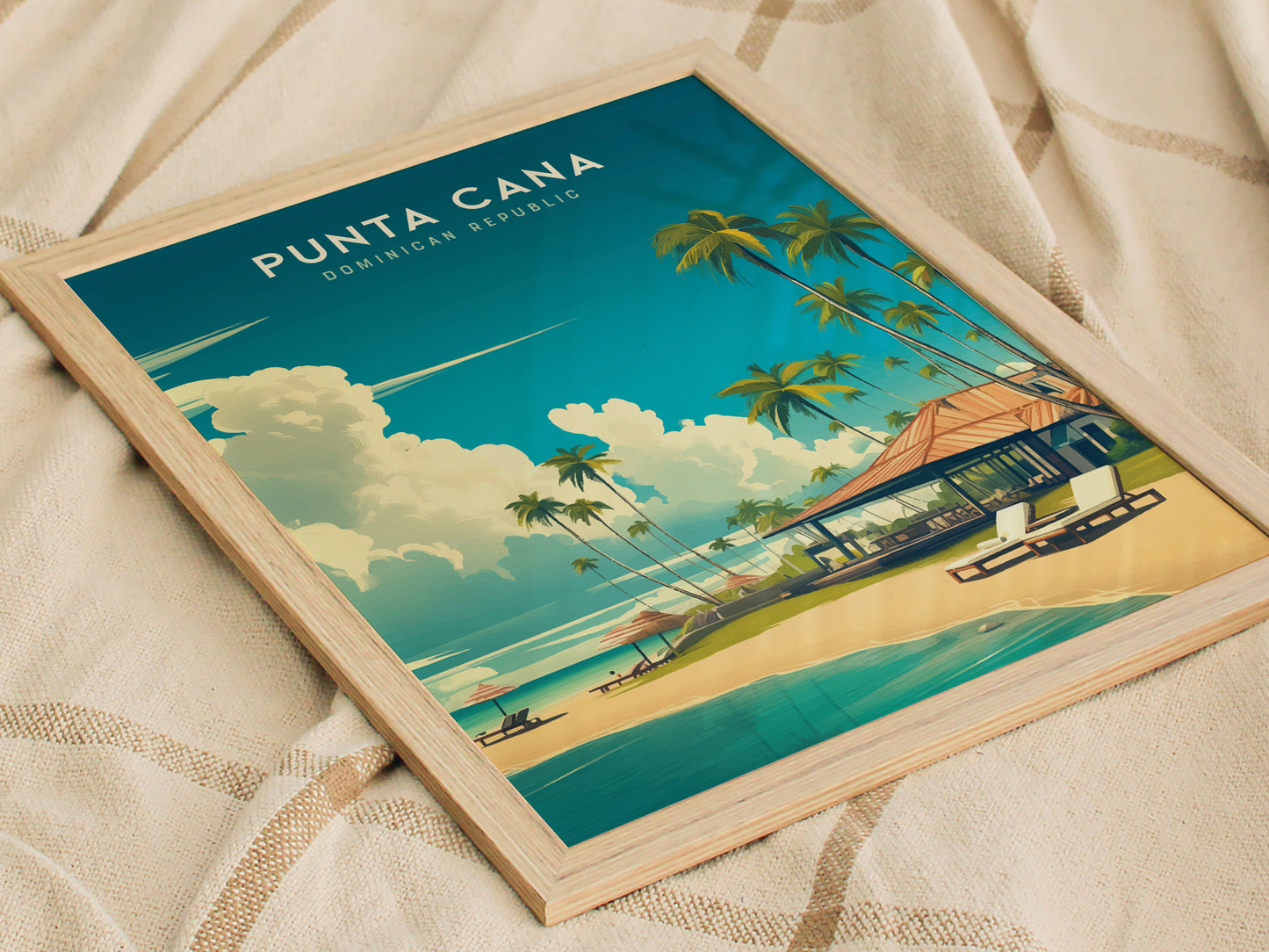 Framed Punta Cana poster featuring a vibrant illustration of a tropical beach with palm trees, a beachside villa, and turquoise waters. The artwork rests on a textured beige fabric, enhancing its Caribbean allure.