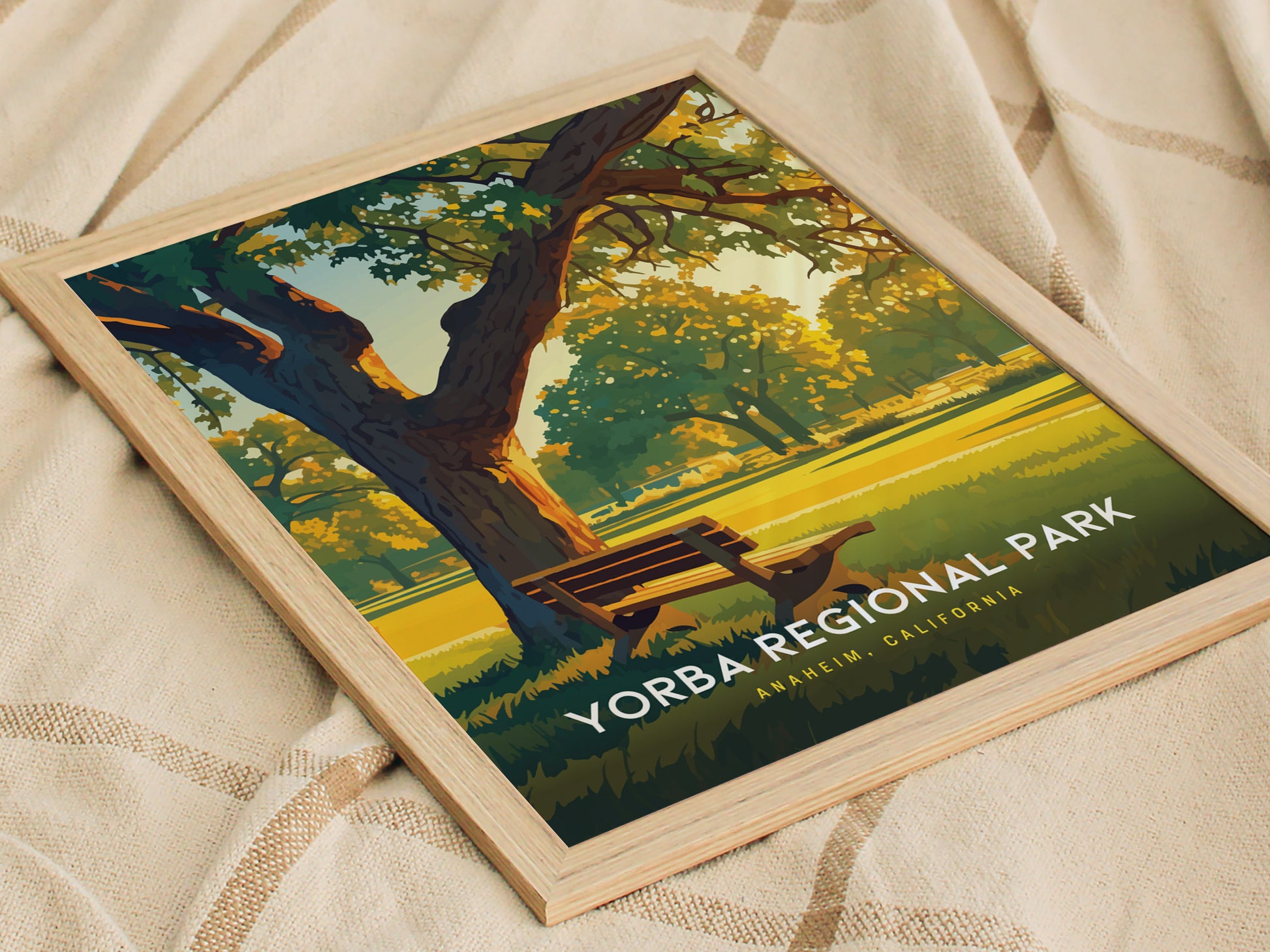 Framed poster of Yorba Regional Park featuring a sunny landscape with a bench under a large tree, placed on a textured fabric surface.