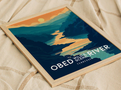A framed poster depicting a stylized landscape of the Obed Wild and Scenic River with blue-green water and orange cliffs, placed on a beige fabric background.