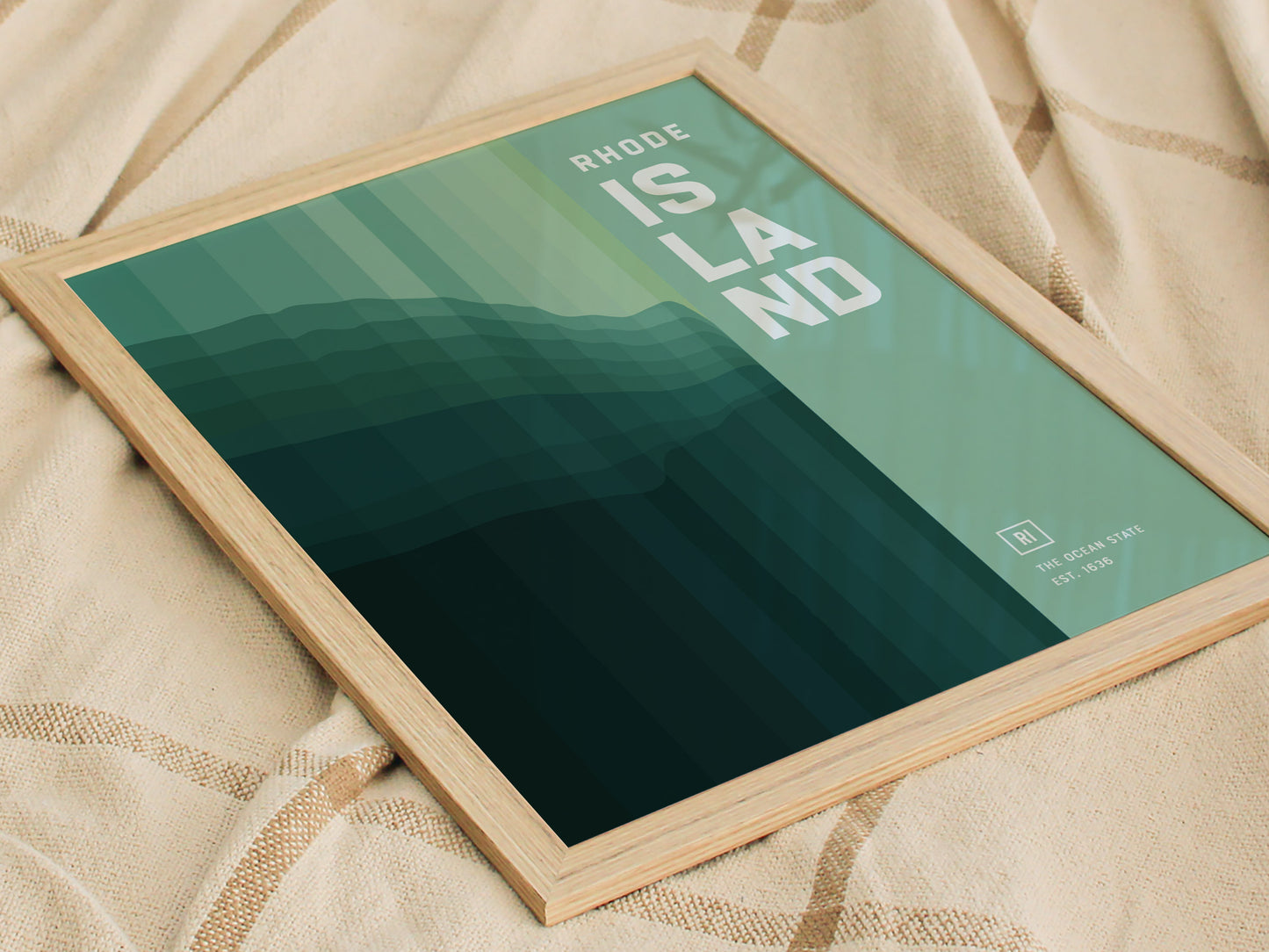 Framed abstract poster with green geometric layers and the words RHODE ISLAND on a textured fabric background. Text reads The Ocean State Est. 1636 in the corner.