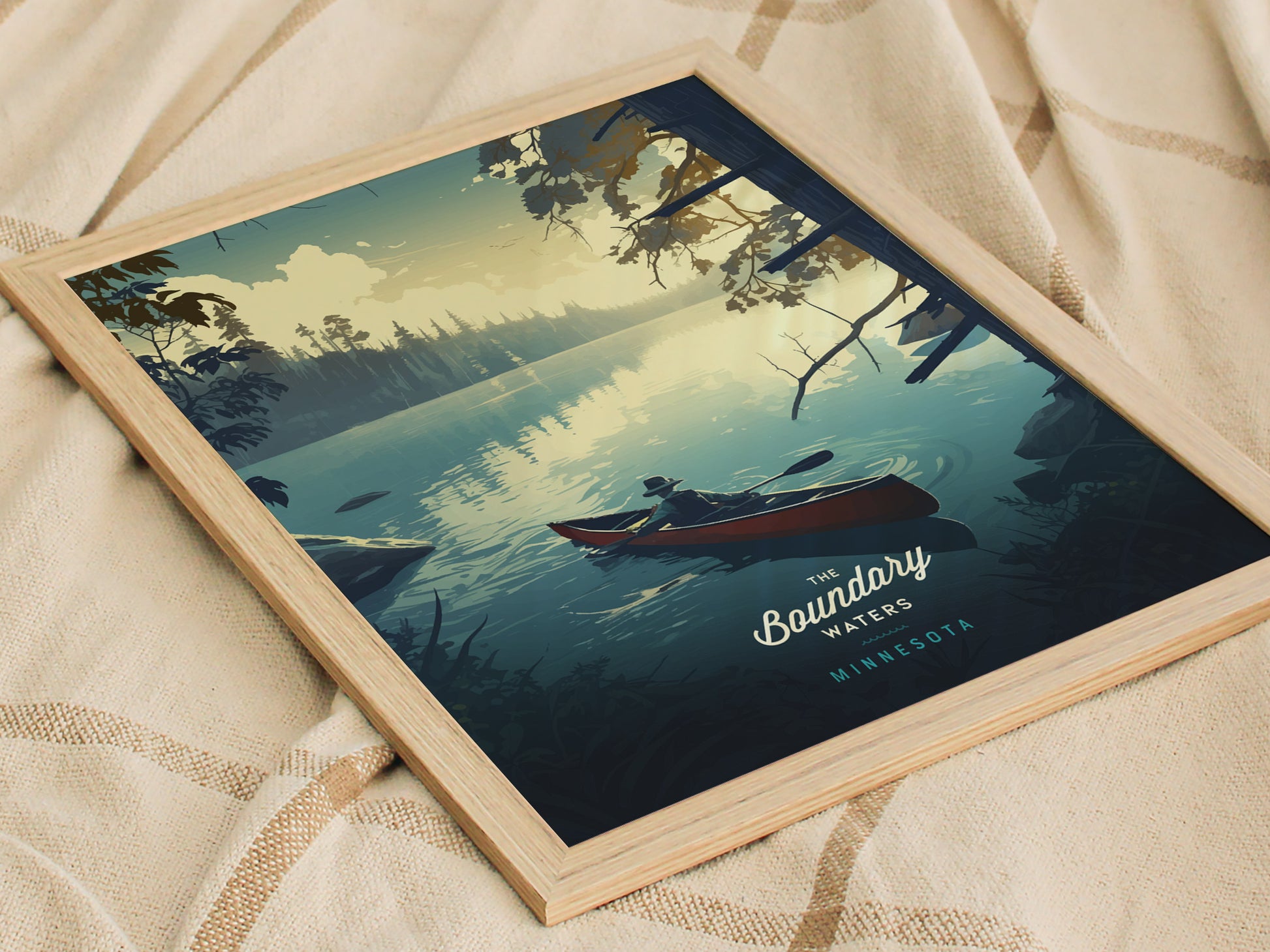 Framed poster depicting a serene lake scene with a person paddling a canoe, surrounded by lush forests and a tranquil sky. The text reads The Boundary Waters Minnesota.