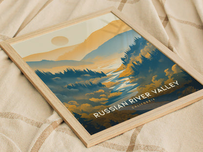 A framed poster titled Russian River Valley, California depicts a scenic landscape with rolling hills, a river, and a sun setting behind the mountains, placed on a textured fabric backdrop.