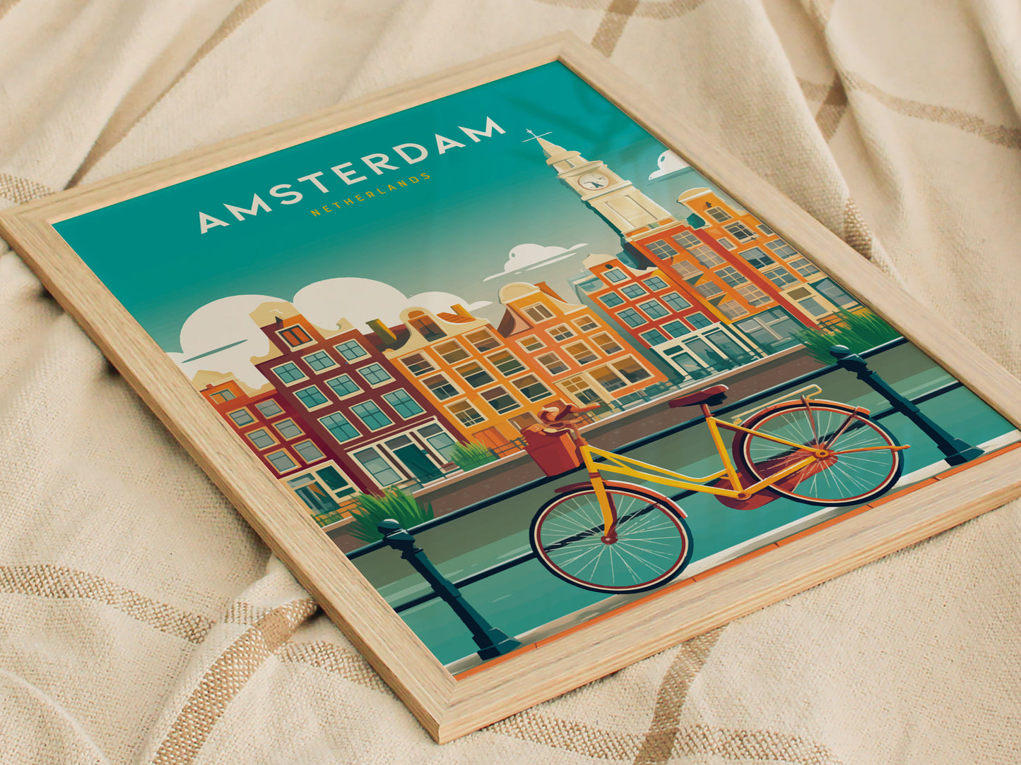 A framed poster of Amsterdam features a vibrant illustration of iconic canal houses in warm colors, with a yellow bicycle parked by the water. The design includes a clock tower and a clear blue sky, capturing the charm of the city.