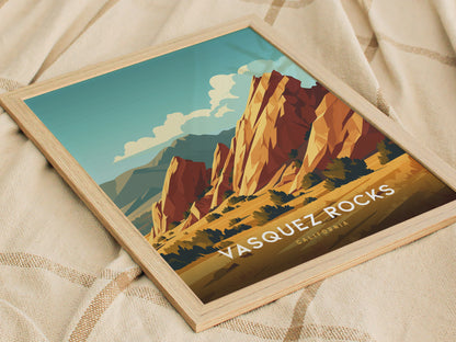 Framed poster of Vasquez Rocks featuring vibrant, stylized sandstone formations under a blue sky, resting on a patterned fabric surface. Text reads Vasquez Rocks, California.