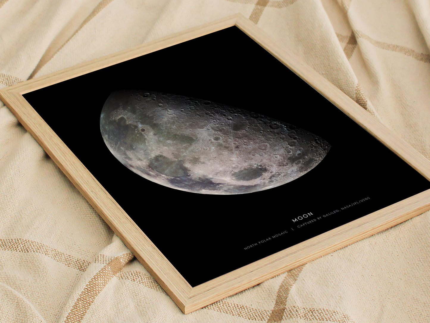 Natural wood framed Moon print leaning on a shelf next to plants and minimalist decor