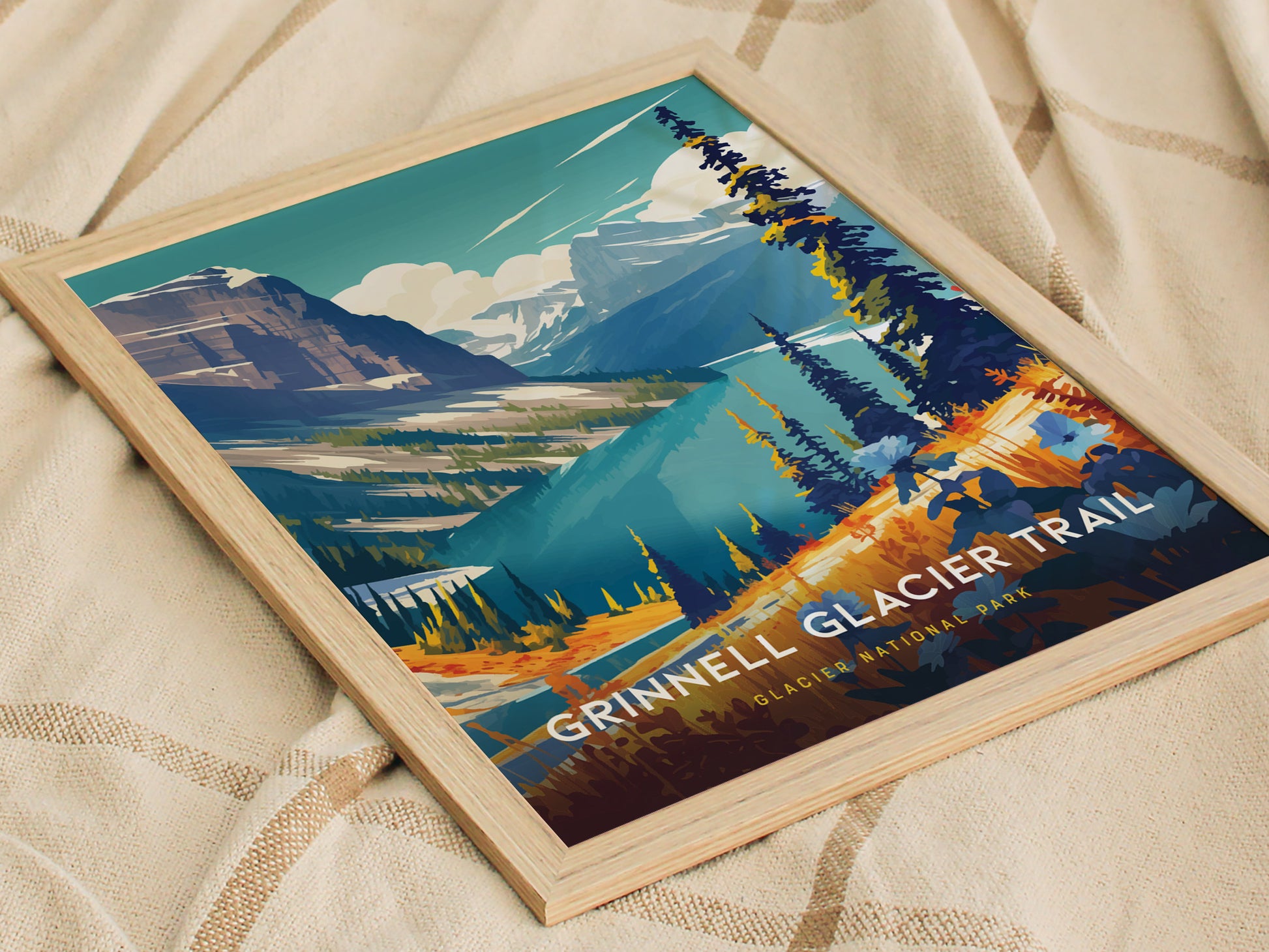 A framed poster of the Grinnell Glacier Trail in Glacier National Park showcases vibrant colors depicting mountains, lakes, and trees, set on a soft, textured fabric background.