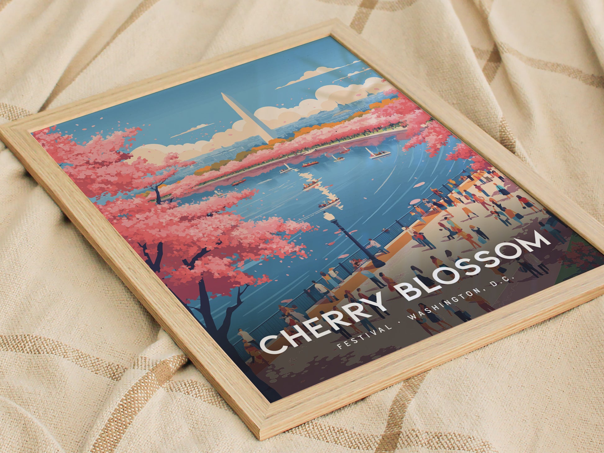 A framed poster depicting cherry blossoms in full bloom by a river, with people walking along the waterfront and a cityscape featuring the Washington Monument in the background. The text reads Cherry Blossom Festival, Washington D.C.